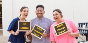 Three students pose with signs.